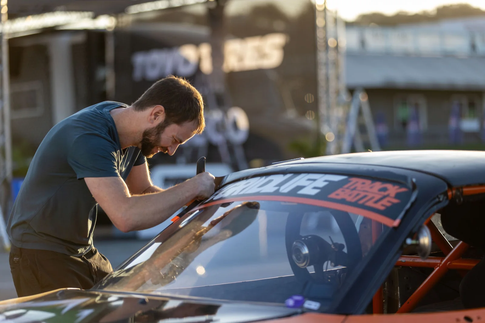 Nick applying the GridLife TrackBattle windshield banner to the Miata