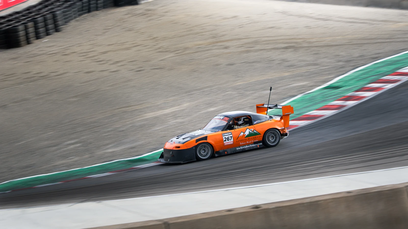 Orange number 267 Miata alongside the curbing at Laguna Seca