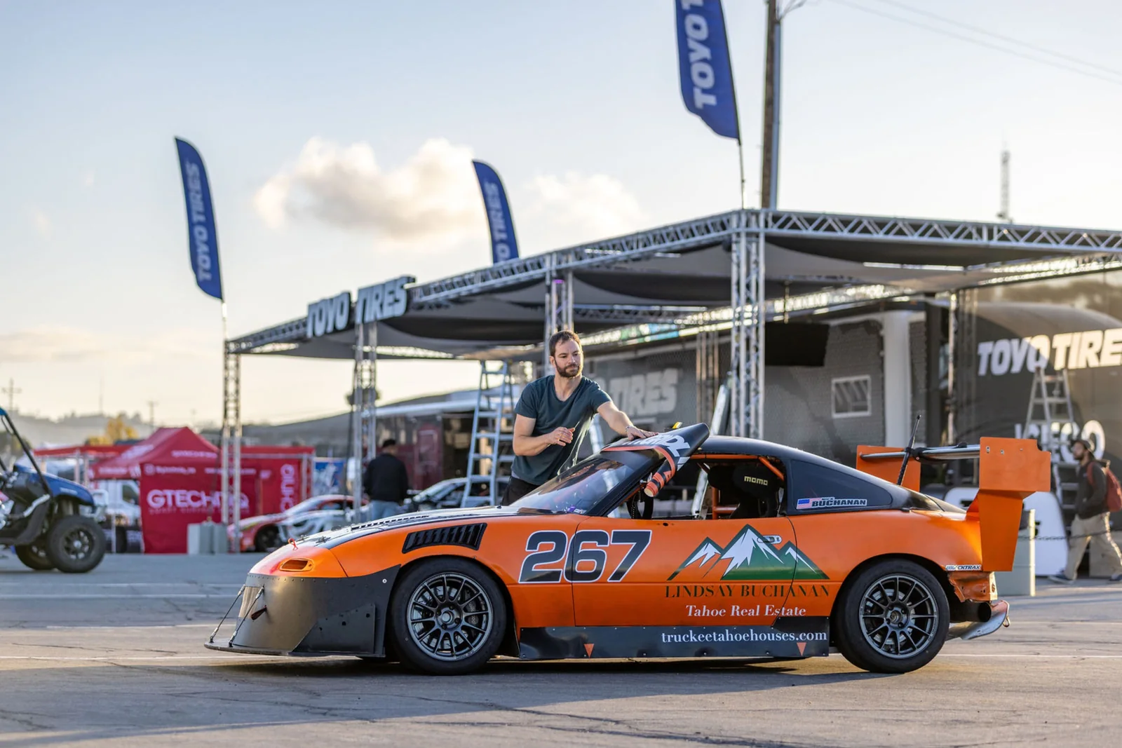 Nick beside the number 267 Miata with its partner livery visible in the paddock